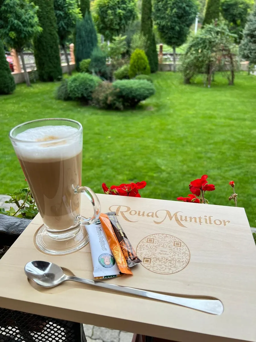 Cafea servită pe terasă, cu însemnul pensiunii