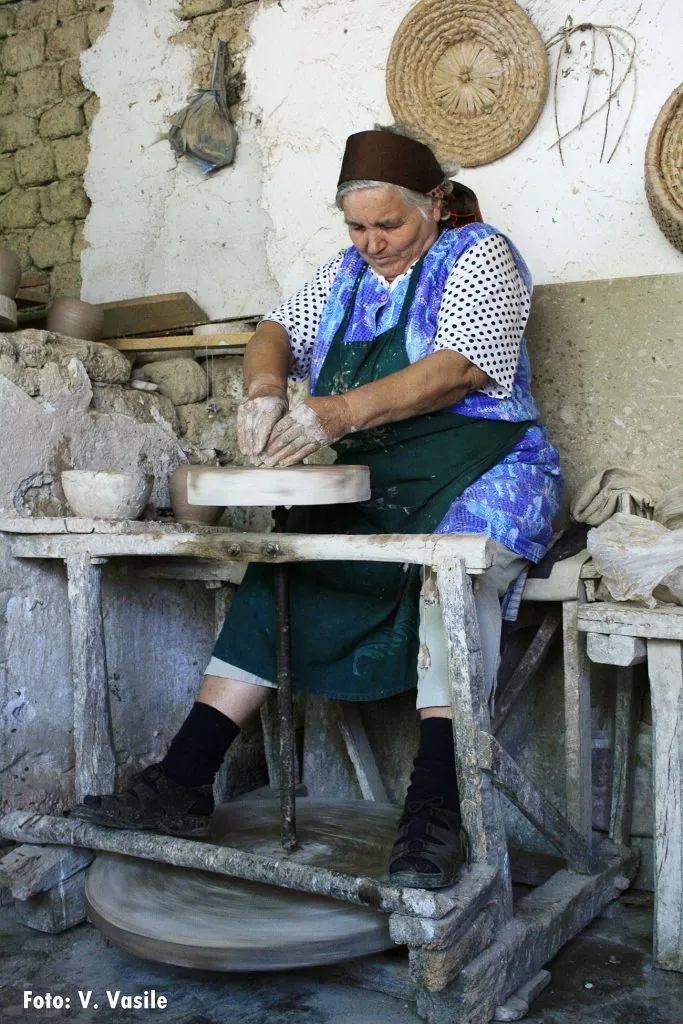 Meșter olar modelând ceramică albă la roată